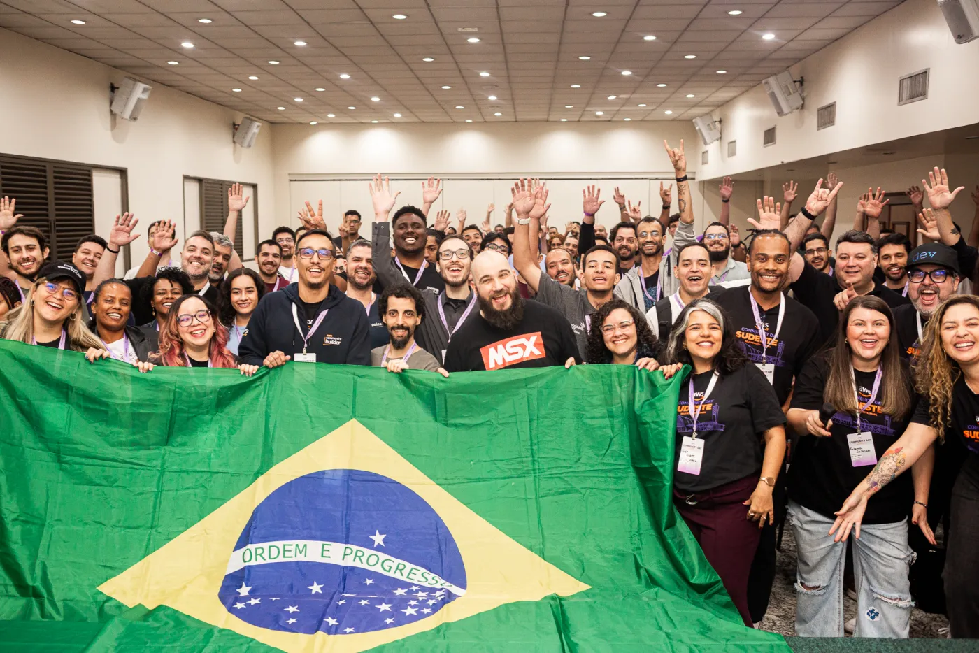 Participantes do AWS Community Day Sudeste posando com a bandeira do Brasil
